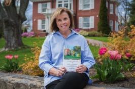 Jan Dean sitting outside of 的 president's house with her book